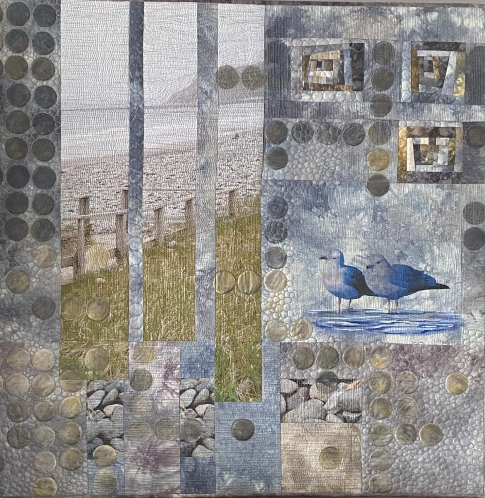 Lawrence town tramps is a large piece showing a digital print of a beach in Nova Scotia, improv log cabin blocks and digital prints pieced by machine using different grey hand dyed fabrics. Plus circles have been rubbed with Paintstiks. A photo transfer of two seagulls standing in water complete the piece.