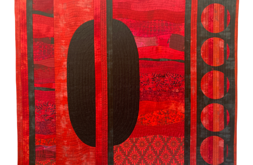 an image showing a textile piece in reds with an oval shape like a door to one side and circles in black on the other side