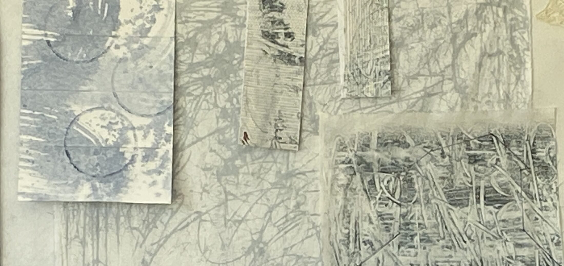 an image showing some pieces of fabric painted with mark making in soft gray blues and grays