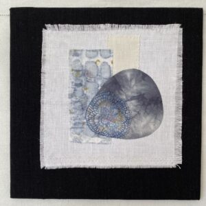 an image showing a small wallhanging mounted on a board of an embellished rocks on linen with two small pieces of linen on the background