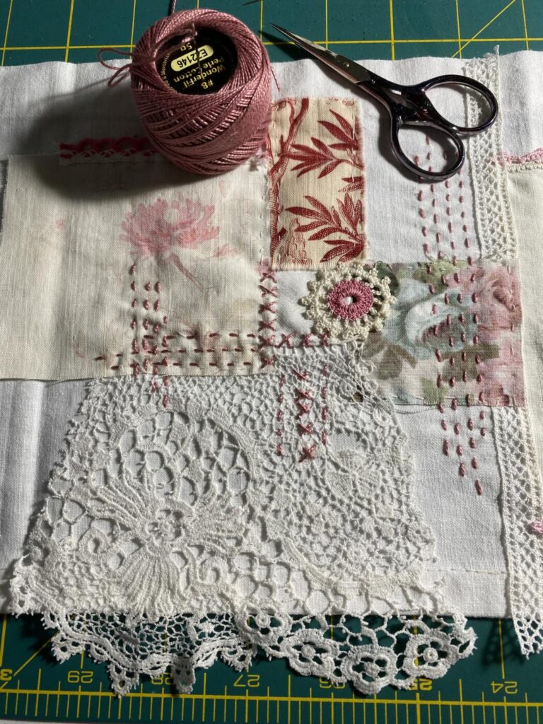 an image showing a piece of vintage fabric with lace and fabrics sewn on to it and lots of stitching with Eleganza embroidery thread no. 8 and a small pair of embroidery scissors