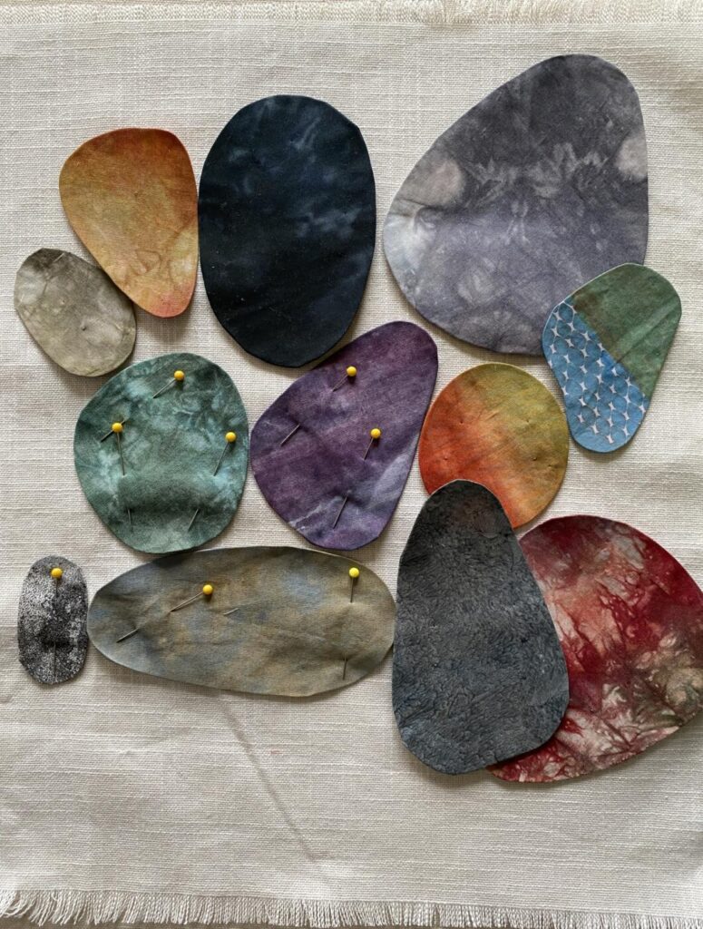 an image showing a piece of frayed linen with a potential composition of rocks of different colours and sizes ready to stitch