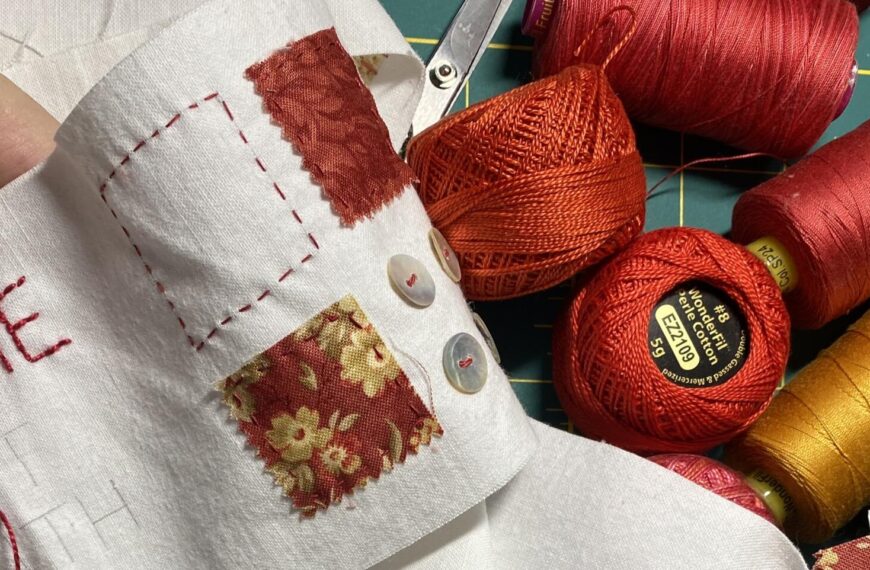 a detail of a hand stitching on a scroll. spools and balls of thread sitting nearby