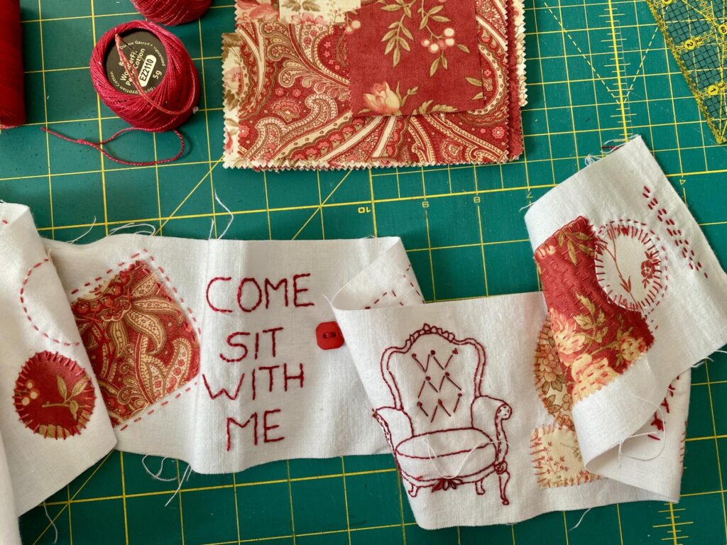 an image showing part of the scroll of fabric with the stitching and pieces of fabric attached to it. A vintage chair has been stitched and it reads come sit with me. a red button completes the composition