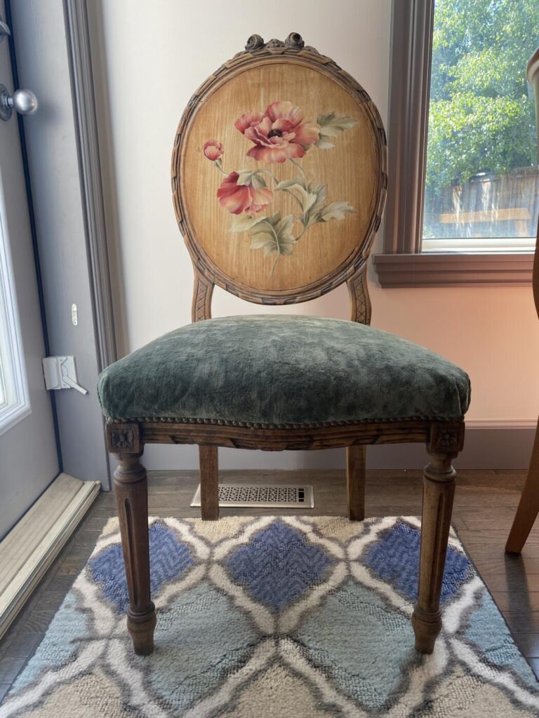 an image showing a vintage chair upholstered in moss velvet with the chair back painted with a peony design