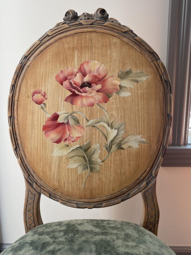 an image showing a vintage chair upholstered in moss velvet with the chair back painted with a peony design - close up