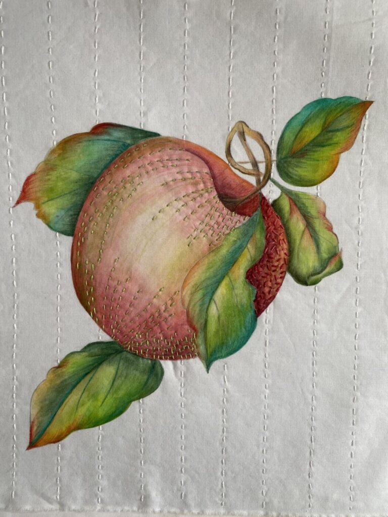 an image showing an apple design on fabric painted with Inktense pencils and embellished with threads
